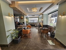Un moderno vestíbulo de hotel con mostrador de recepción, zona de estar y amplias ventanas con vistas a la ciudad.