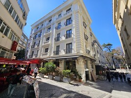 Un hotel con fachada clásica, varios balcones y una calle adoquinada frente a él.