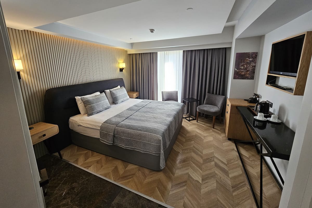Una habitación de hotel moderna con una cama grande, un escritorio, una silla y una mesita.