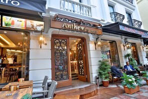 The exterior of the Anthesis Hotel with ornate ironwork, a wooden entrance, and outdoor seating with potted plants. - Anthemis Hotel (Istanbul)