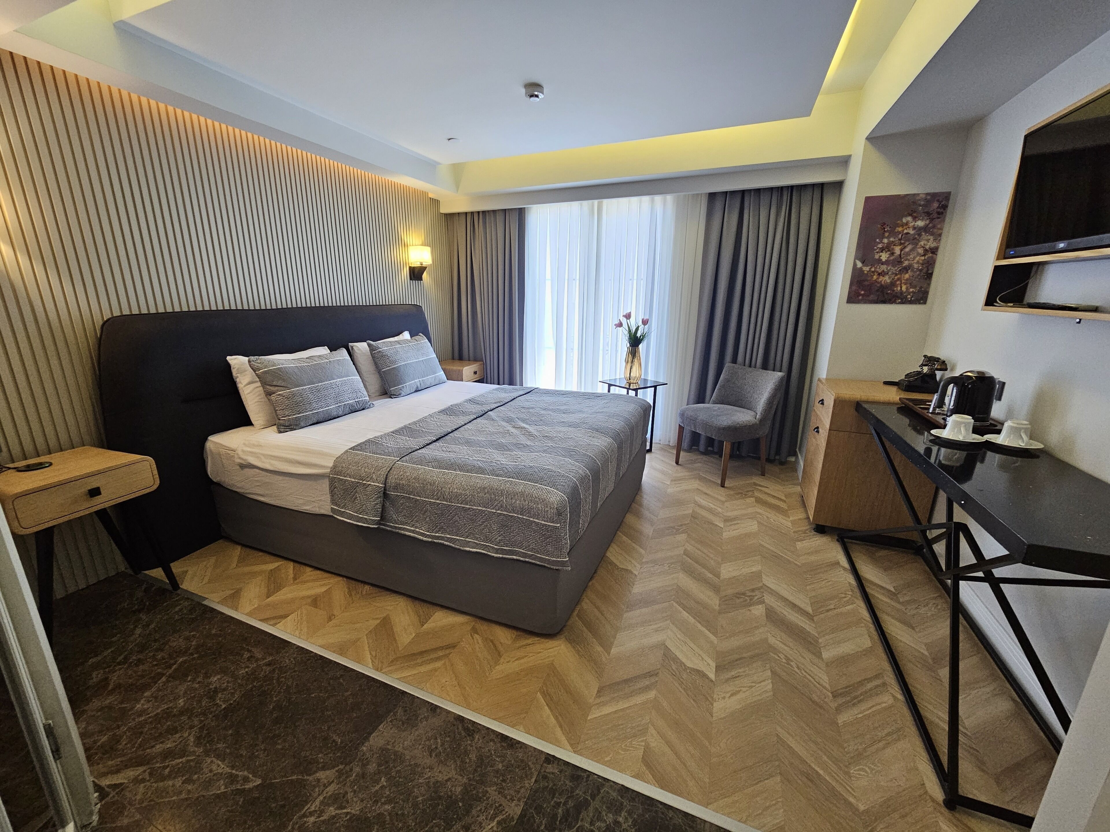 A modern hotel room with a large bed, a desk, and a chair.