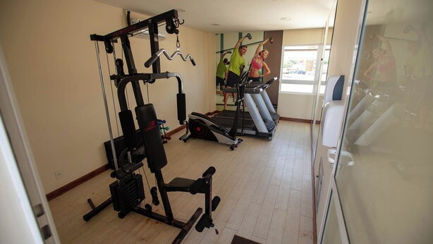 A gym with cardio machines, weightlifting equipment, and a mirrored wall. - Rede Andrade Express (Salvador)