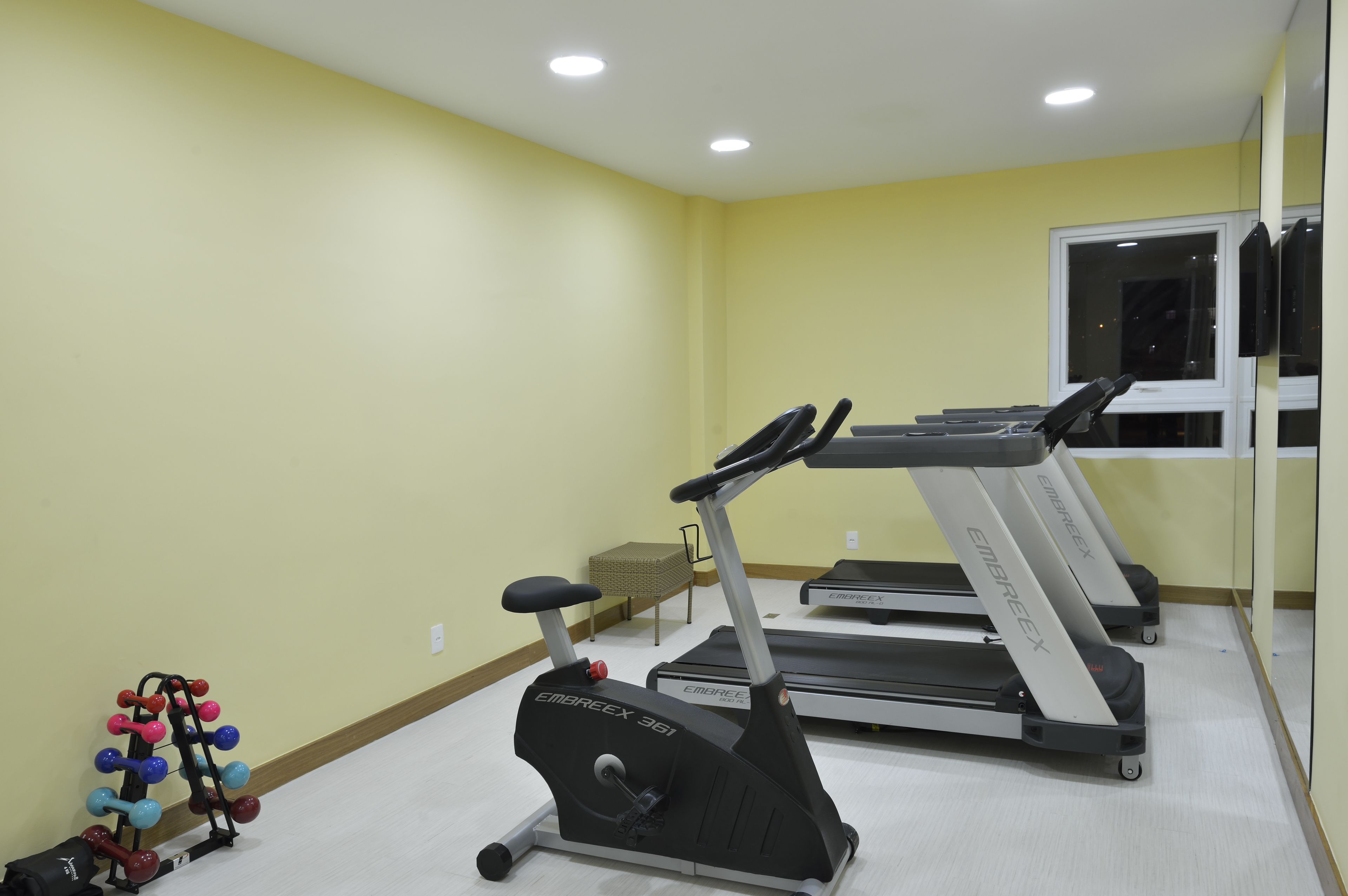 A gym with treadmills, a stationary bike, and a set of dumbbells.