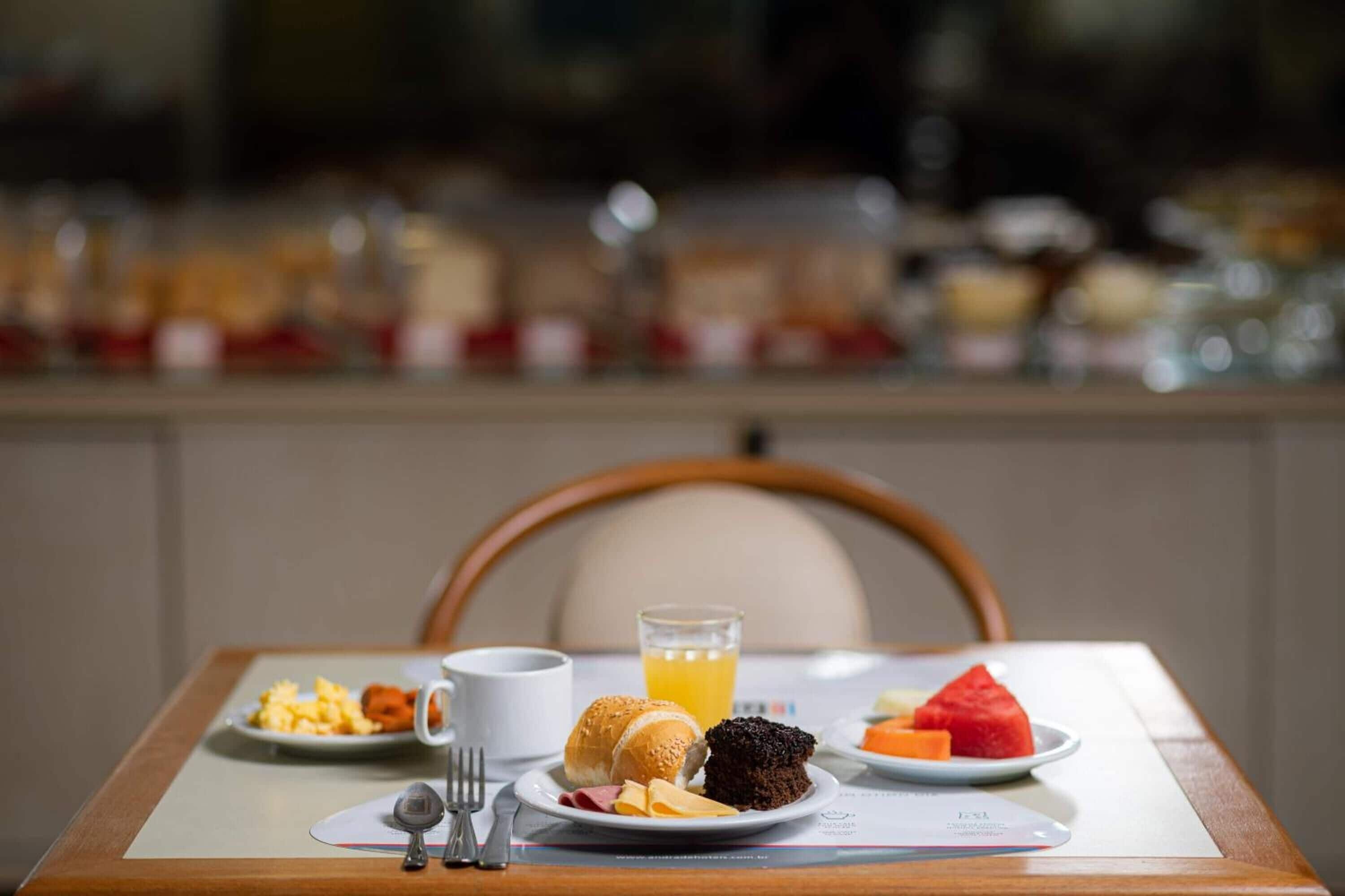 A breakfast tray with eggs, a croissant, a slice of cake, a glass of orange juice, and a plate with a slice of watermelon.