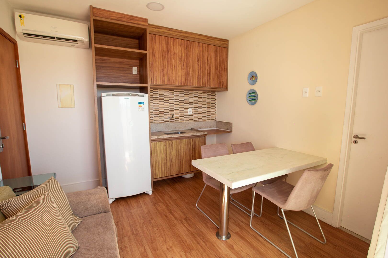 A compact kitchen with a built-in refrigerator, wooden cabinets, and a small dining table.