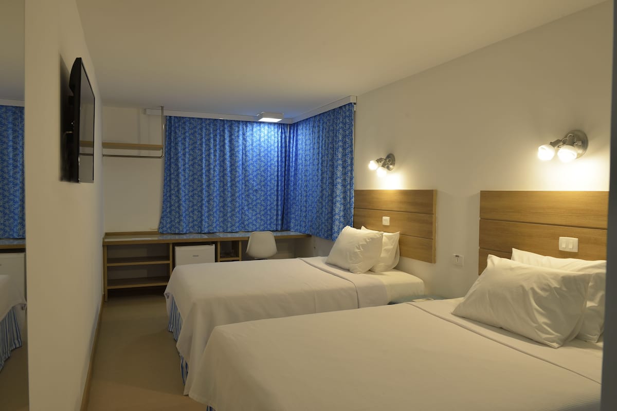 Una habitación de hotel con dos camas, un escritorio, una silla y un espejo.