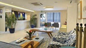 A modern hotel lobby with a reception desk, seating area, and a view of the ocean. - Rede Andrade Express (Salvador)