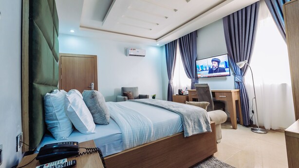 Un dormitorio moderno con cama, escritorio y televisión.