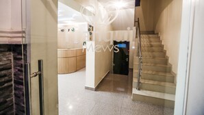 Un moderno vestíbulo de hotel con un mostrador de recepción, una escalera y un vidrio que da a una habitación.