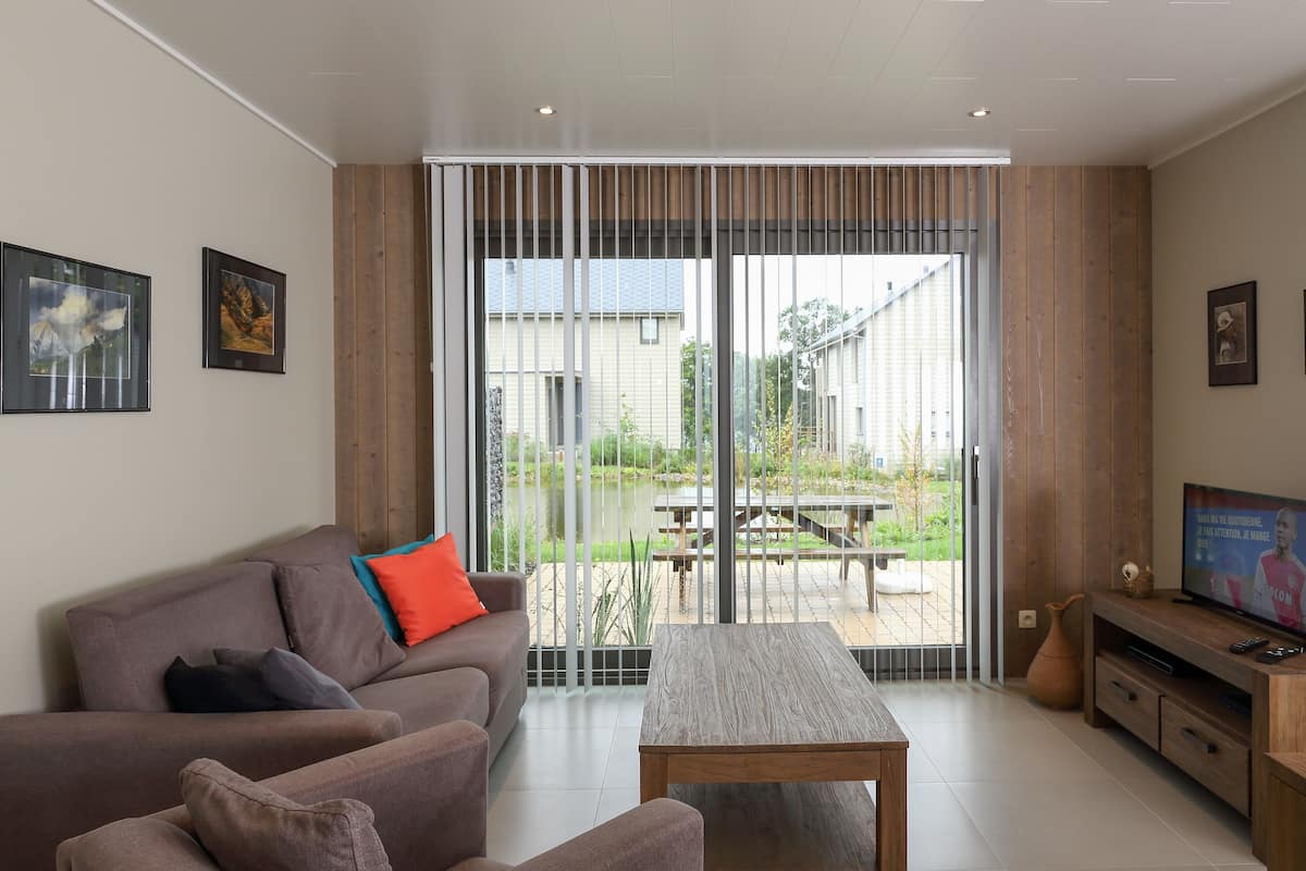 A modern living room with a sofa, coffee table, and a TV on a wooden stand.