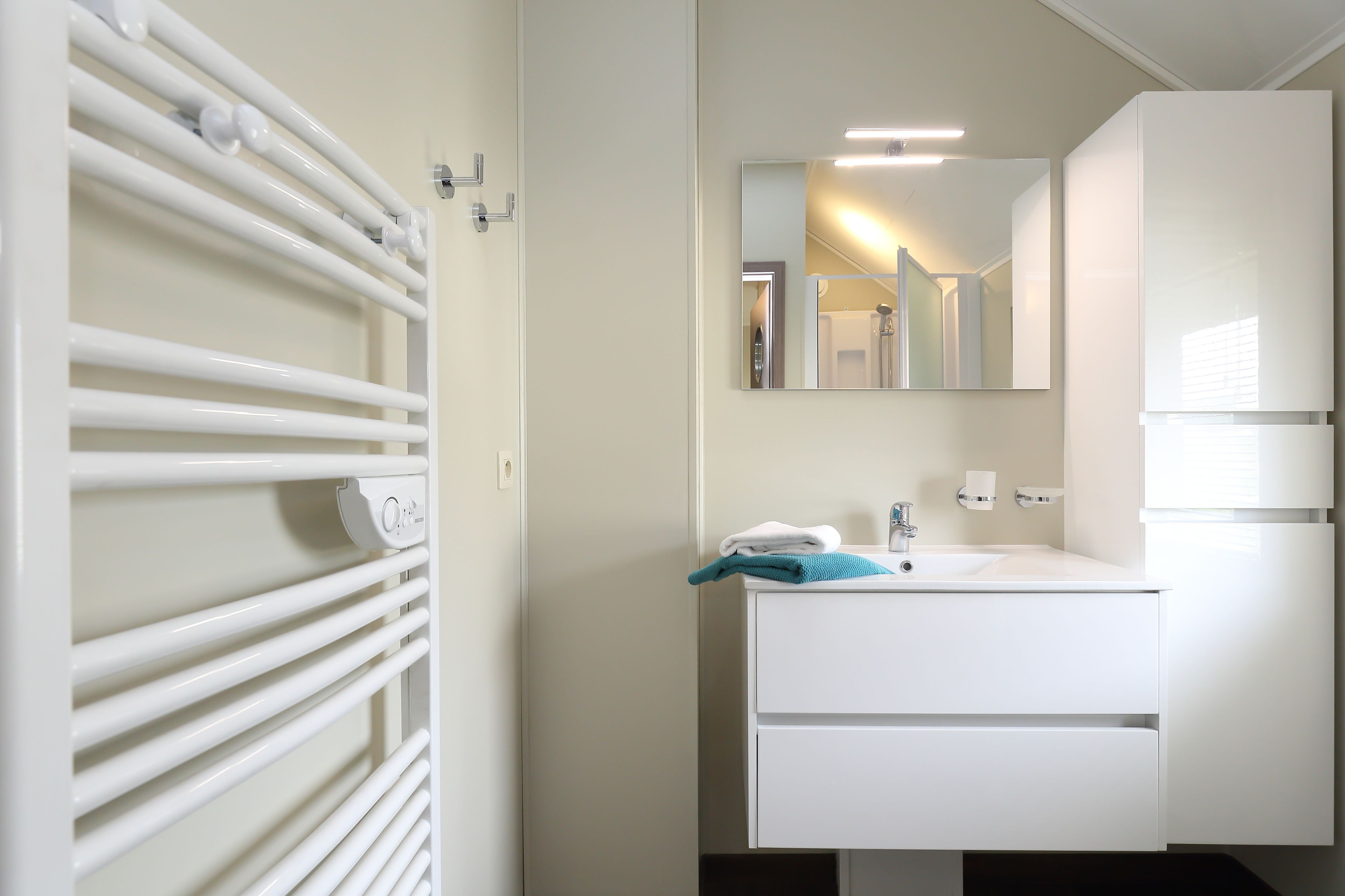 Een moderne badkamer met een wit wastafelmeubel, spiegel en handdoekhouder.