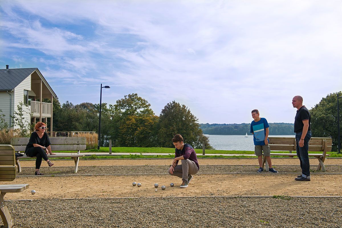 A group of people playing croquet in a park with a lake in the background.