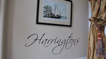 A framed photograph of a coastal scene with a building and a boat, and the word "Harringtons" written below it.
