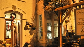 A building with a porch, potted plants, and a signboard. - Harringtons at Fourteen (Llandudno)