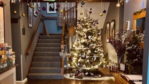 A staircase leading to a second floor, a Christmas tree decorated with ornaments, and a reception desk with a sign. - The Churchill Court (Witney)