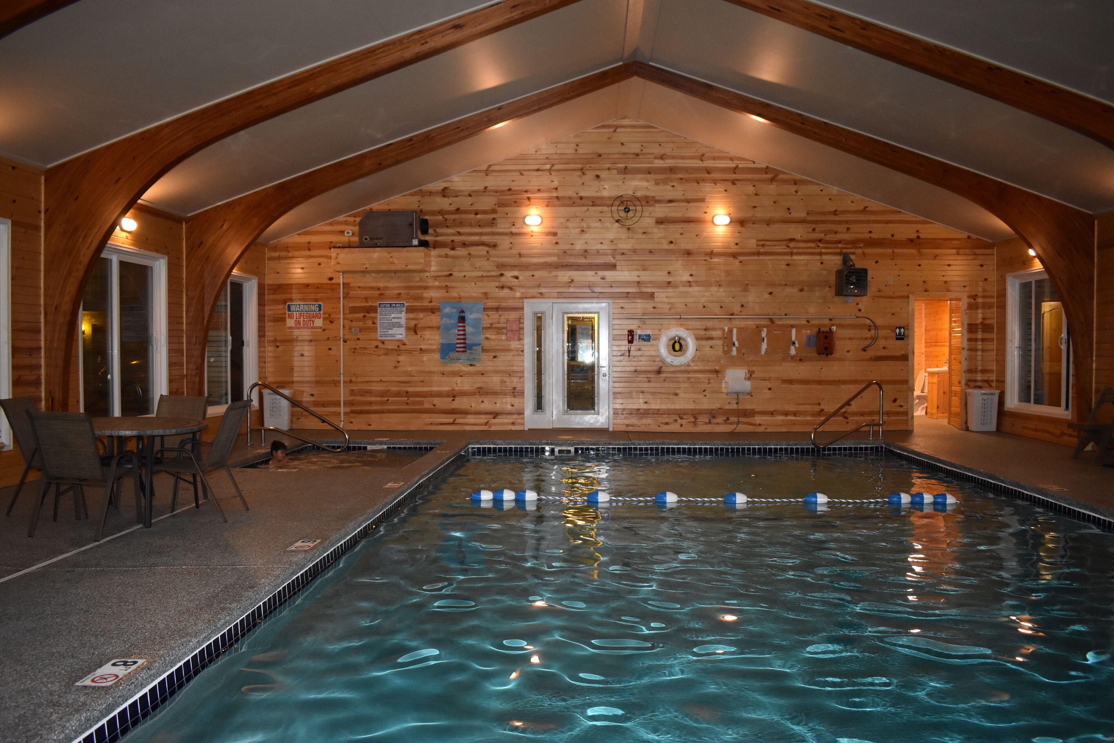 An indoor swimming pool with wooden walls and a vaulted ceiling.