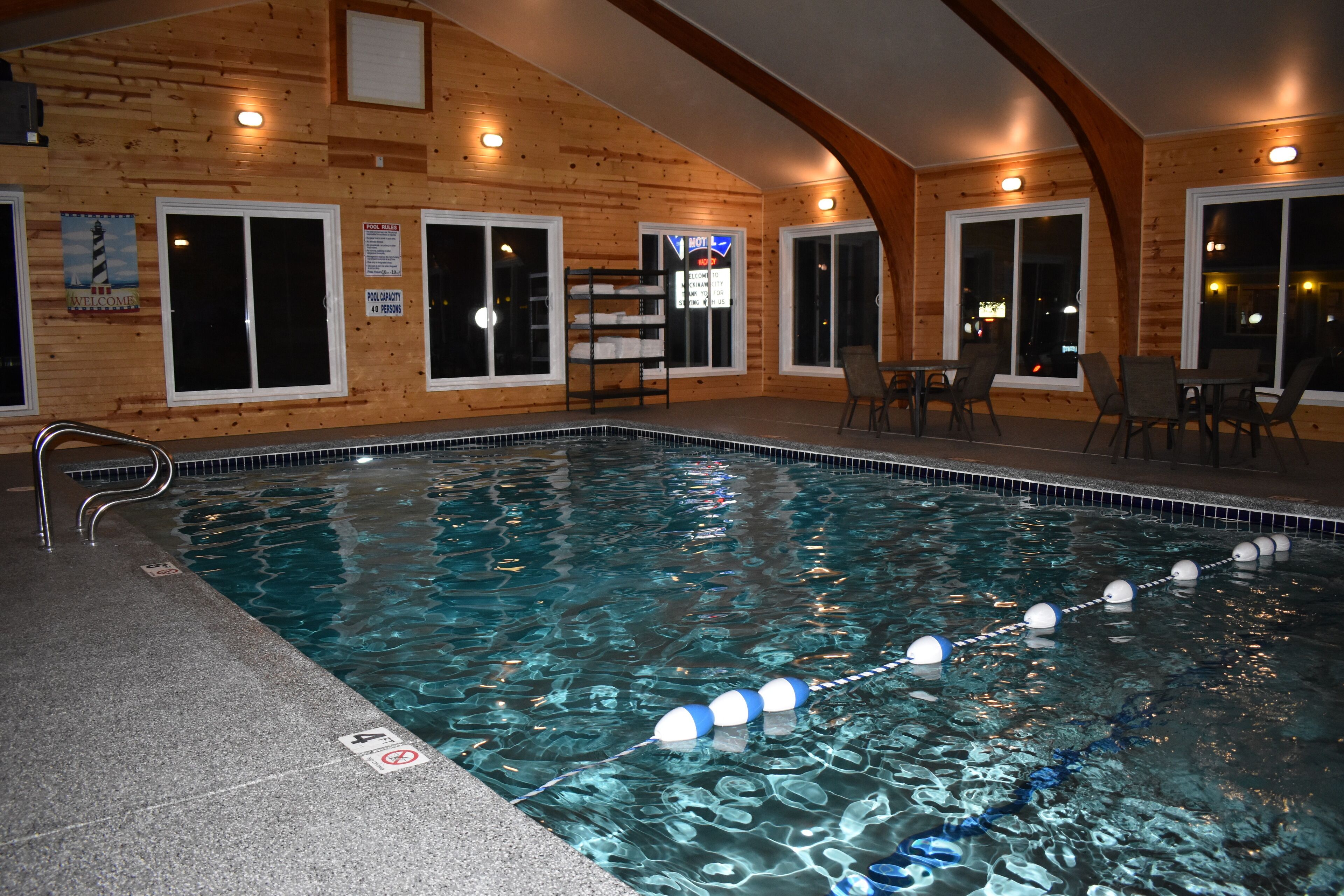An indoor swimming pool with clear water, wooden walls, and a pool ladder.