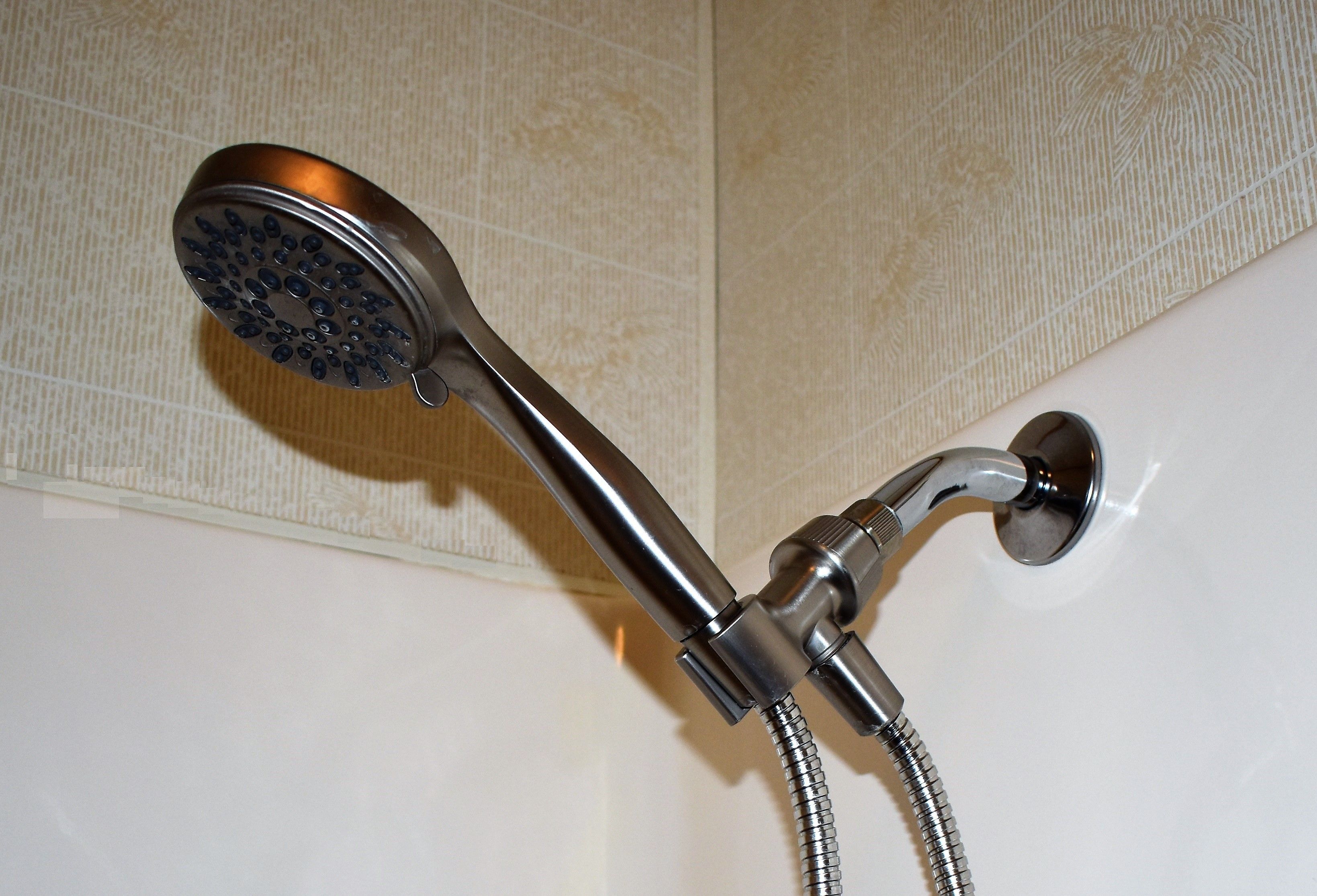A showerhead with a flexible hose attached to a wall-mounted faucet.