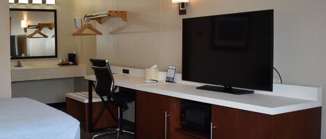 Habitación de hotel con dos camas, un escritorio con televisor, una silla, una lámpara de escritorio, un teléfono y un espejo.