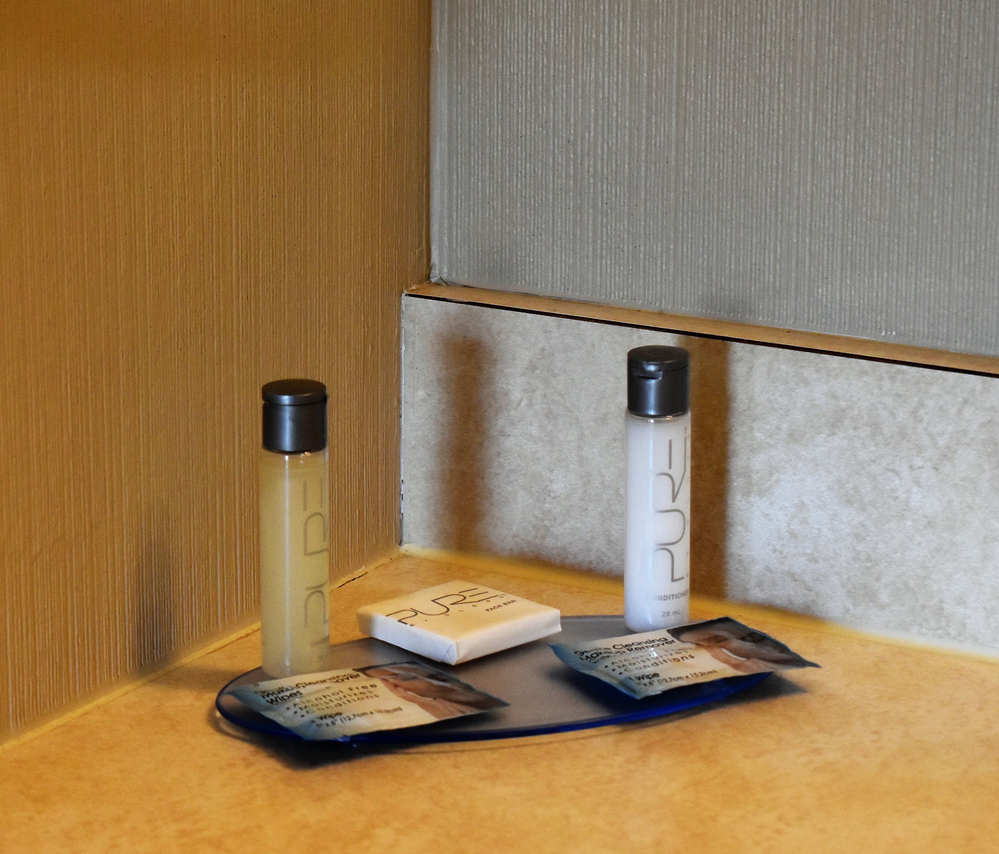A small table with two bottles of liquid, a box, and a packet of wipes.