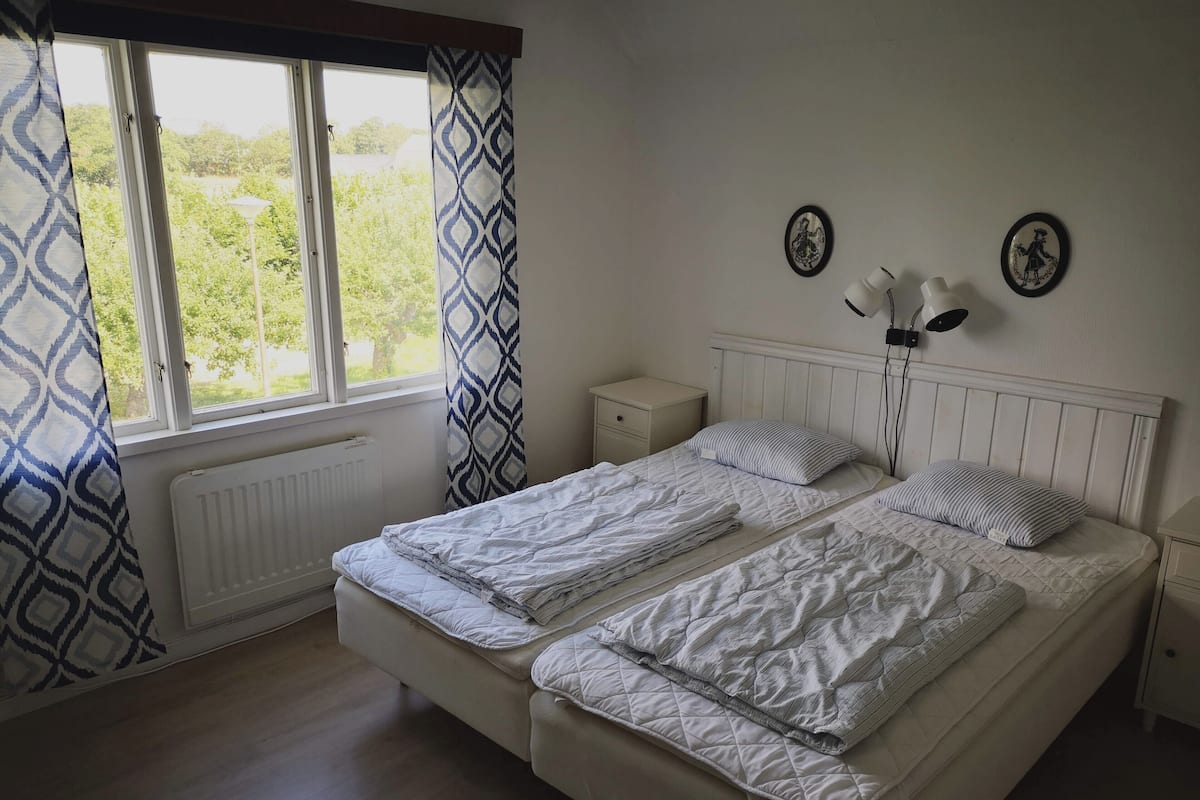 A bedroom with a double bed, a bedside table, a nightstand, a radiator, and two wall-mounted lamps.