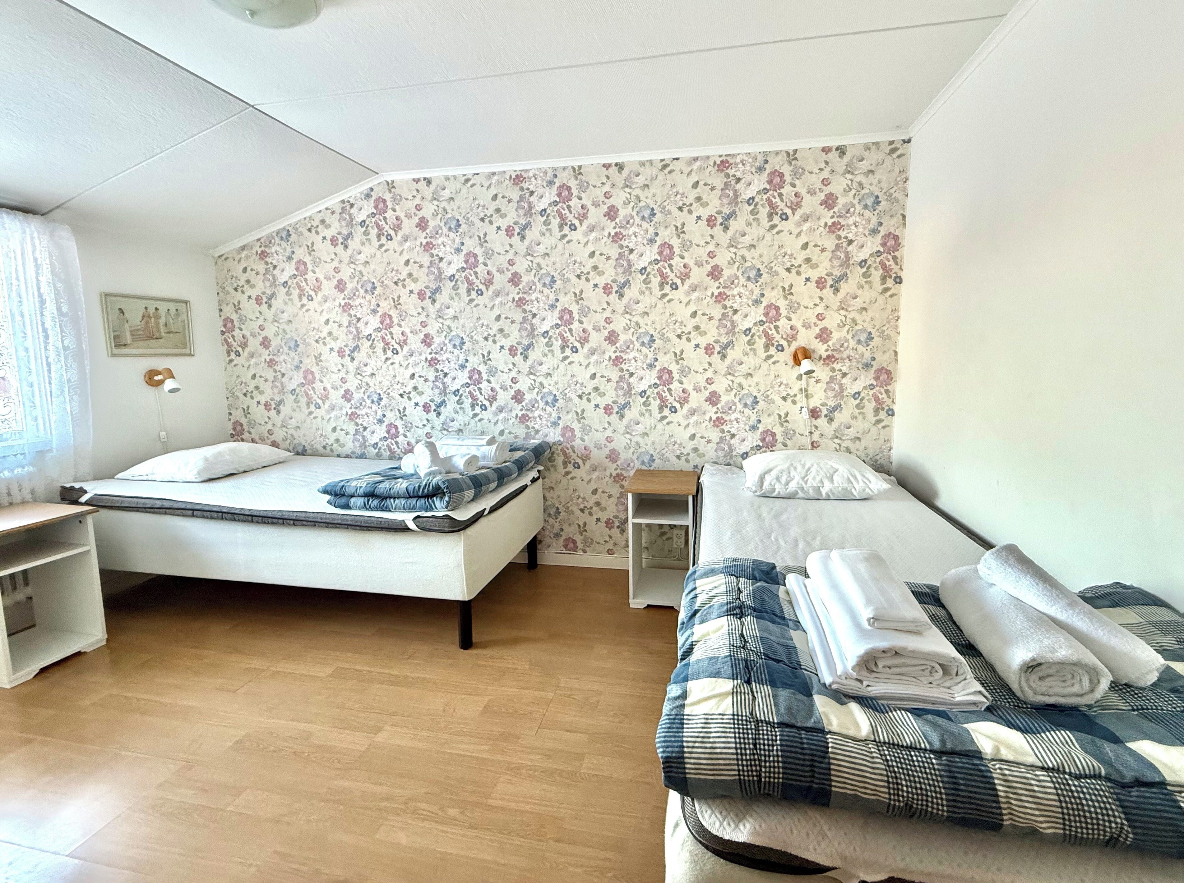 Una camera da letto con un letto, un comodino, una sedia e una parete con carta da parati a motivi floreali.