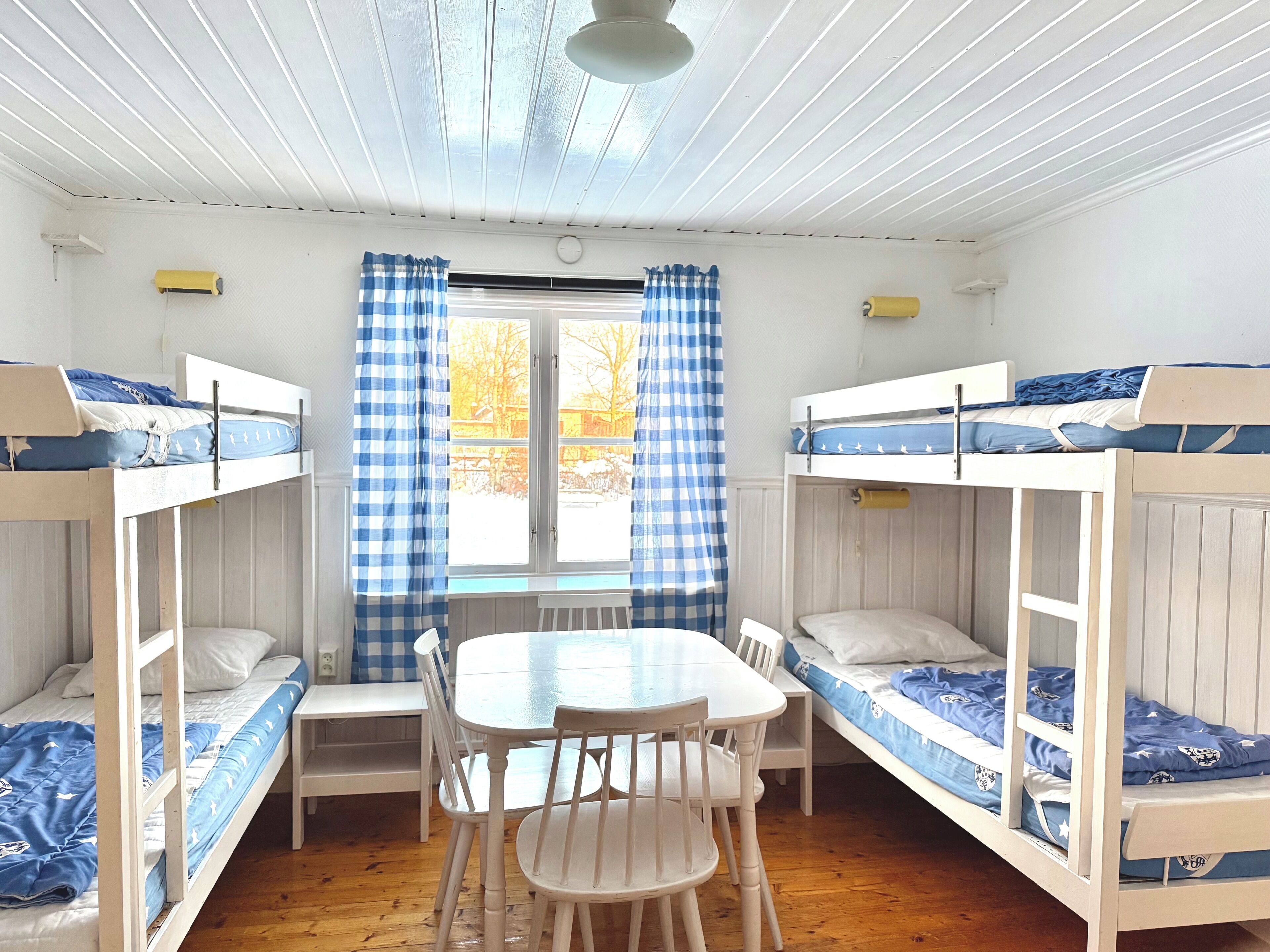 A dormitory room with bunk beds, a small table, and chairs.