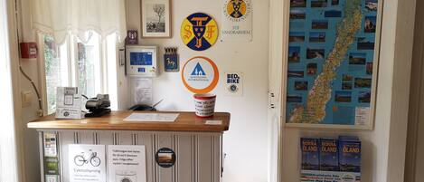 A reception desk with a map, a sign for a 50 kr/3-timars pass, and a notice about a 150 kr/600 kr/weekly laundry service.
