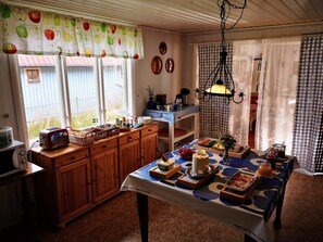 Una cocina acogedora con armarios de madera, una mesa dispuesta con comida y un ventanal con vistas a un jardín.
