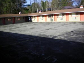 A motel with a large parking lot and multiple rooms with orange and beige exteriors.