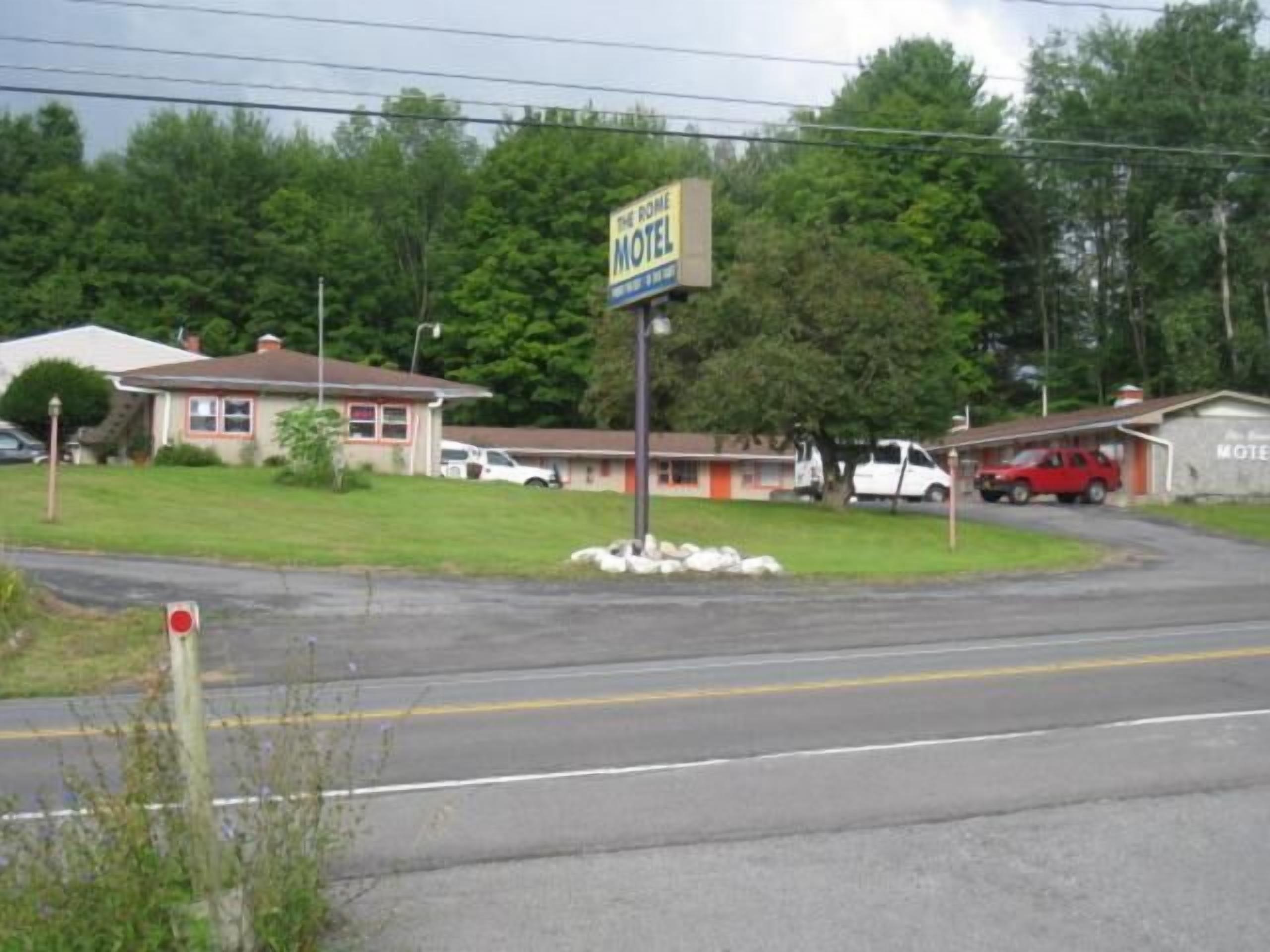 A motel with a signboard, a parking area, and a road.