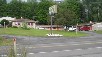 A motel with a signboard, a parking area, and a road.