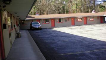 A motel with a covered parking area and a row of rooms with red trim.