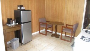 A compact kitchen with a refrigerator, a small table, two chairs, and a gas stove. - The Rome Motel (Rome)