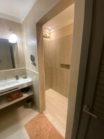 A modern bathroom with a dual sink vanity, a mirror, and a shower area.