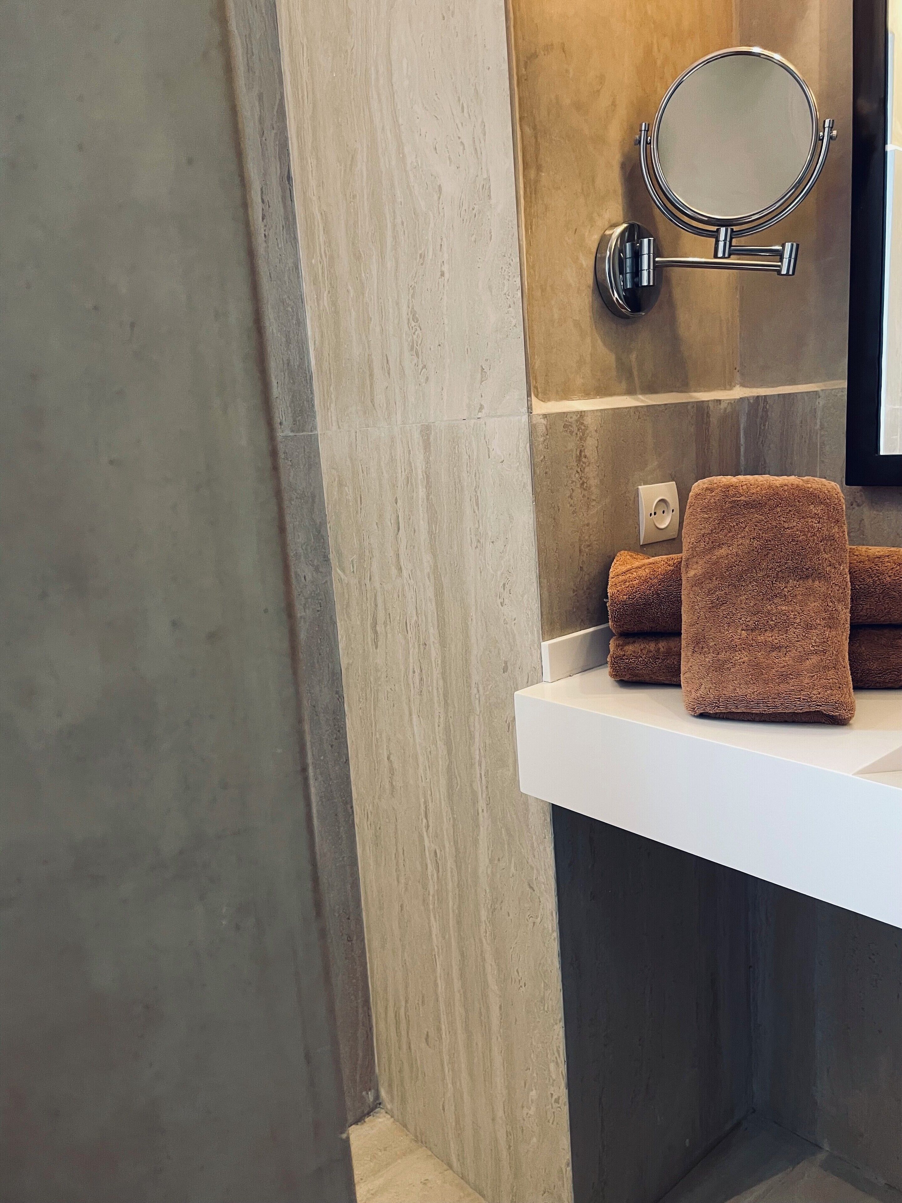 A bathroom with a white sink, a round mirror, and a towel rack.