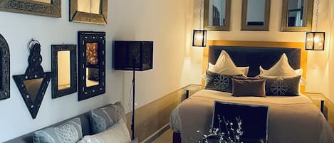 A bedroom with a large bed, a sofa, and multiple wall-mounted mirrors.