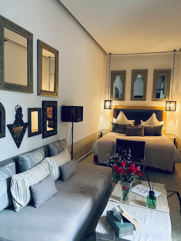 Ein Schlafzimmer mit einem großen Bett, einer Couch und mehreren Wandspiegeln.