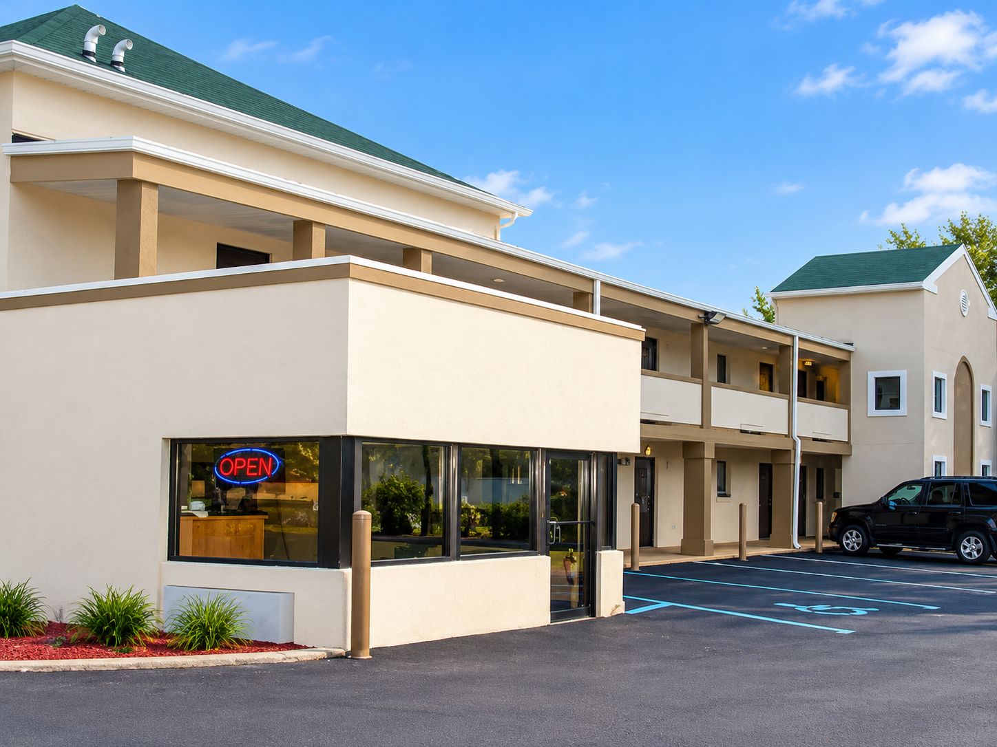 A two-story building with a flat roof, a visible 'OPEN' sign, and a parking lot with marked spaces.