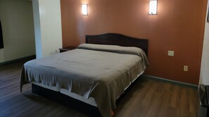 Une chambre à coucher avec un lit, deux lampes fixées au mur et un plancher en bois.