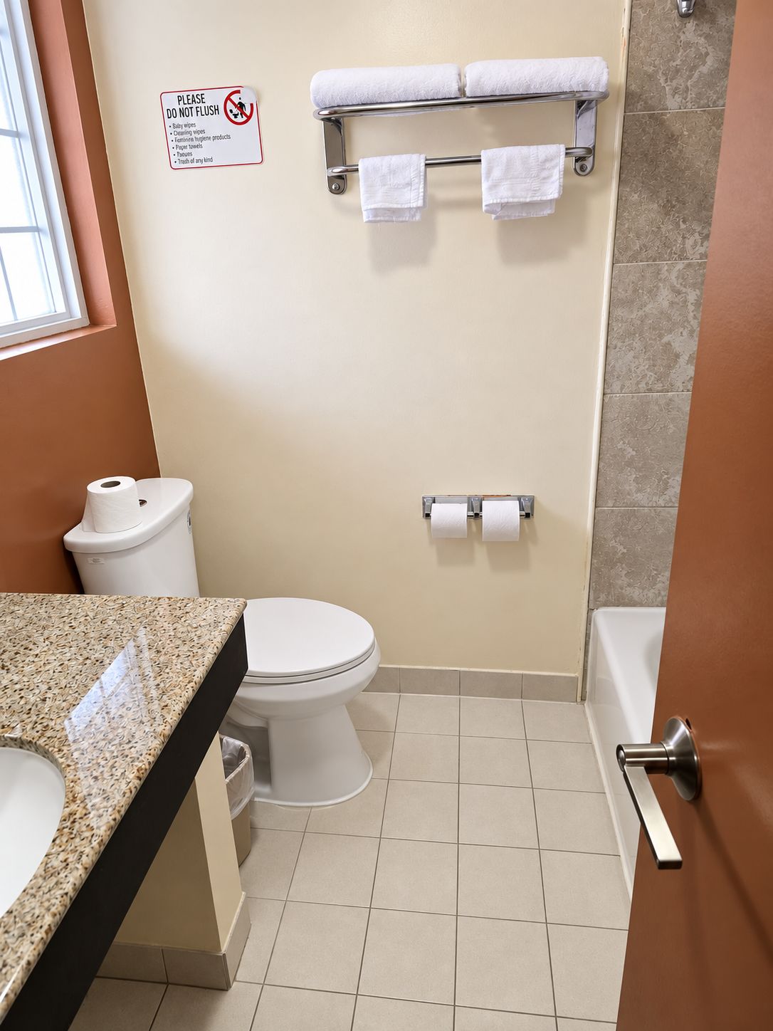 Un baño con inodoro, lavamanos, toallero y un cartel que prohíbe tirar pañales húmedos y productos de higiene femenina.