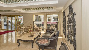 A spacious lobby with a high ceiling, a central seating area with a sofa and chairs, a marble coffee table, and ornate wall decorations. - Escardin Hotel (Istanbul)