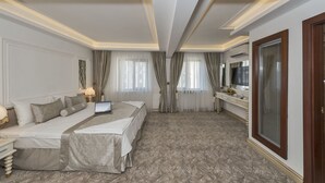 A hotel room with a large bed, a desk, a TV, and a large window with curtains. - Escardin Hotel (Istanbul)