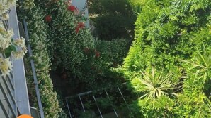 A balcony with lush greenery and a tiled roof in the background. - Hotel Kostis (Skiathos)