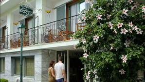 A hotel entrance with a balcony, a signboard, and a potted plant. - Hotel Kostis (Skiathos)
