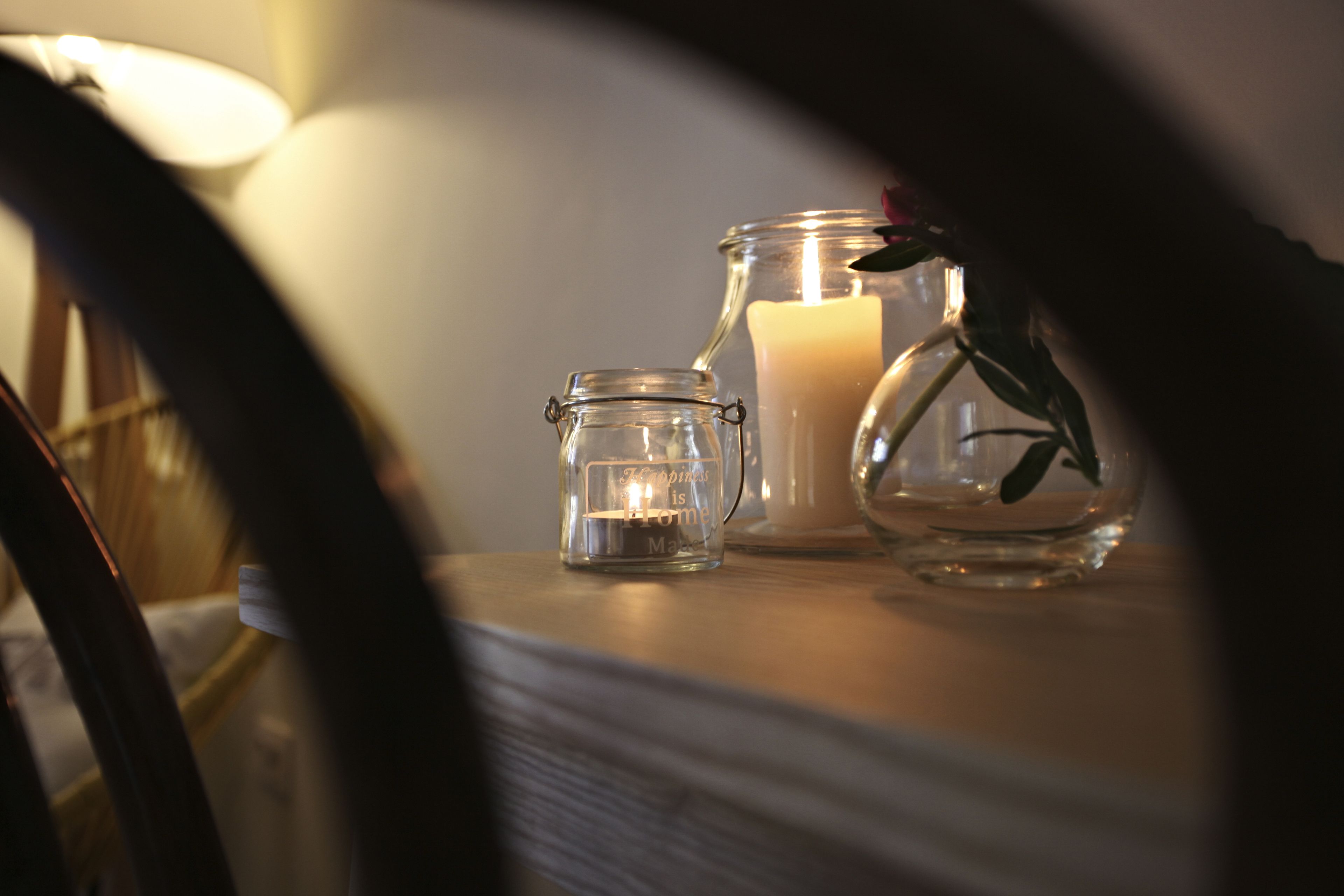 A candle in a glass jar and a larger candle on a table.