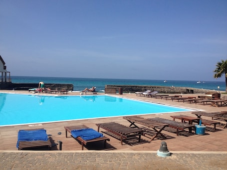 Una piscina al aire libre, sillones reclinables de piscina