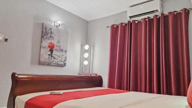 Ein Hotelzimmer mit einem Bett, einem roten Vorhang, einer Wandlampe und einem Gemälde vom Eiffelturm.
