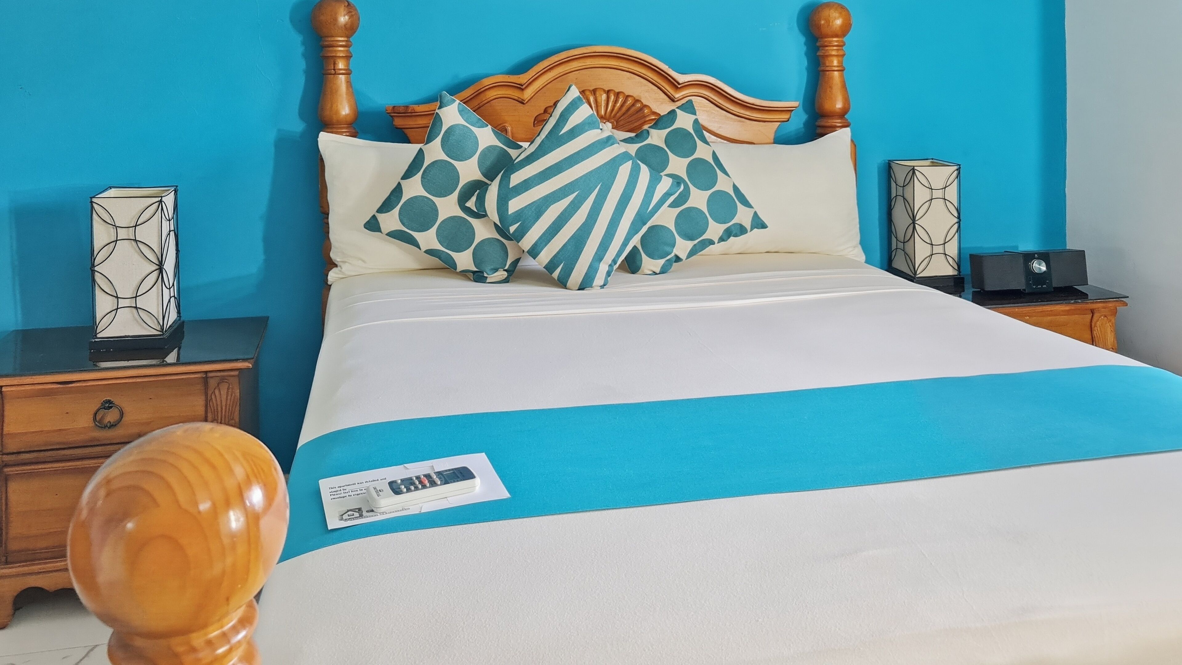 A bed with a blue and white bedspread, wooden headboard, and matching pillows.