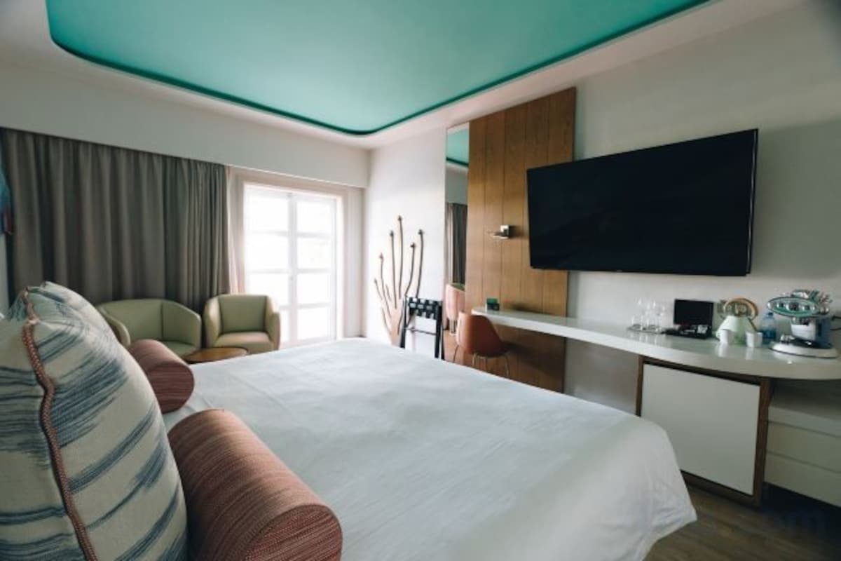 Habitación de hotel con cama, escritorio, televisión y zona de estar.